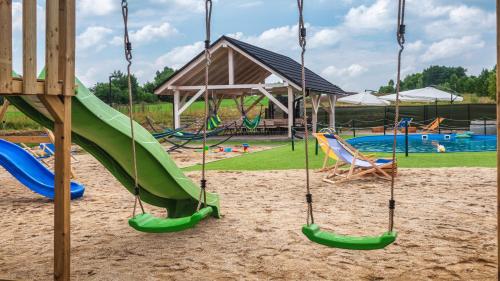 a playground with swings and a slide in the sand at Resorts H Białka Tatrzańska z sauną, Sun & Snow in Białka Tatrzanska