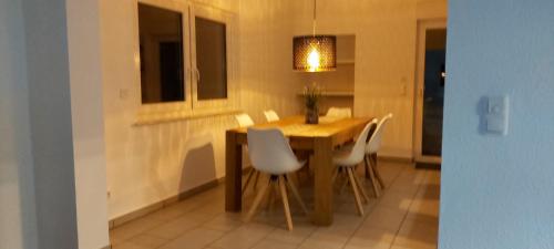 a dining room table with white chairs and a light at Ferienwohnung KaMa in Bitburg