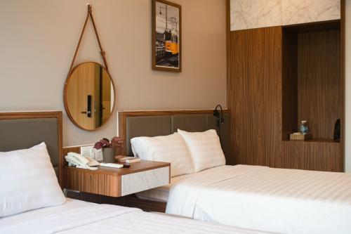a hotel room with two beds and a mirror at West Lake Hotel - Near Bai Dai Beach in Thủy Triều