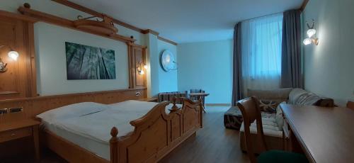 a bedroom with a large bed and a living room at Hotel Comfort Erica Dolomiti Val d'Adige in Salorno sulla Strada del Vino