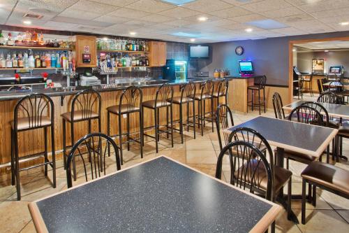 a restaurant with tables and chairs and a bar at AmericInn by Wyndham Aberdeen Event Center in Aberdeen