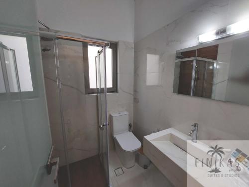 a bathroom with a shower and a toilet and a sink at Finikas Suites & Apartments Airport By Airstay in Artemida