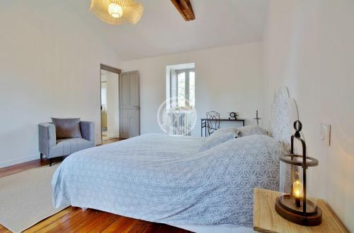 a white bedroom with a large bed and a chair at villa corina in Tarbes