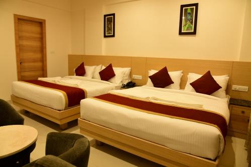 a hotel room with two beds and a table at Hotel U.T.ELITE in Bengaluru