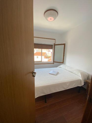 a small bedroom with a bed and a window at Amplio apartamento en el centro de O Grove in O Grove