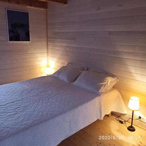 - une chambre avec un lit blanc et 2 lampes dans l'établissement Une Tiny House à découvrir au cœur de la cité !, à Contrexéville