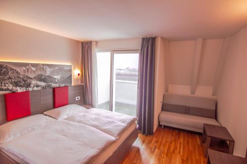 a bedroom with a bed and a large window at Hotel Comfort Erica Dolomiti Val d'Adige in Salorno sulla Strada del Vino