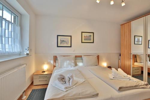 1 dormitorio con 1 cama blanca grande y toallas. en Strandvilla Strandvilla Appartement 7, en Scharbeutz