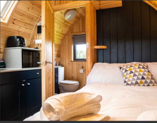 a bedroom with a bed in a wooden cabin at Robins Nest Glamping Pod with Hot Tub in Keith
