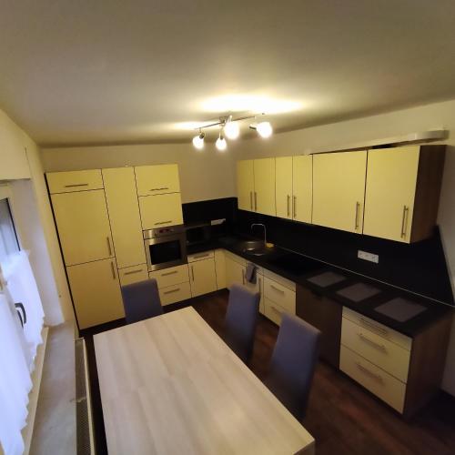 a kitchen with white cabinets and a table and chairs at Wohnung Neunkirchen 2 in Neunkirchen am Brand