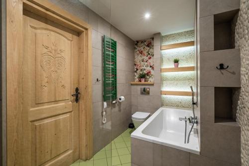 une salle de bain avec une baignoire et des toilettes et une porte dans l'établissement Lux apartamenty Stara Polana, à Zakopane