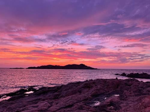 a sunset over the ocean with an island in the distance at Sea Shell Isola Rossa in Isola Rossa