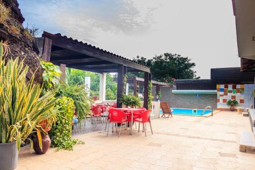 a patio with red chairs and a table and a pool at Pousada Quinta Ribeirinha in Cidade Velha