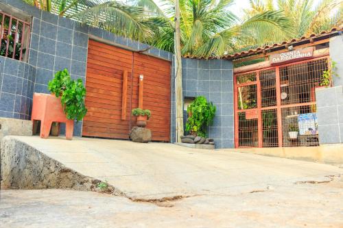 a store front with a red door and palm trees at Pousada Quinta Ribeirinha in Cidade Velha
