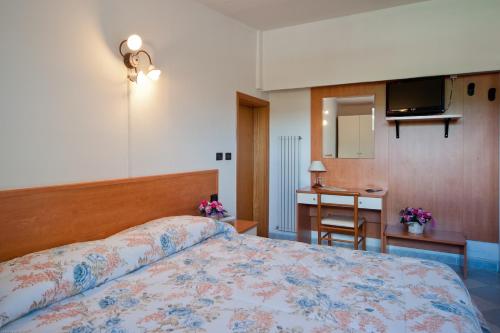 a bedroom with a bed and a desk and a kitchen at Hotel Il Quadrifoglio in Cascia
