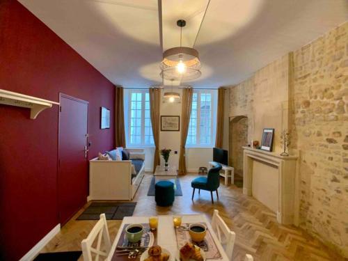 un soggiorno con pareti rosse, tavolo e sedie di Hello Bayeux - Confort dans le coeur de la ville a Bayeux