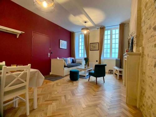 Il comprend un salon doté de murs rouges et de parquet. dans l'établissement Hello Bayeux - Confort dans le coeur de la ville, à Bayeux