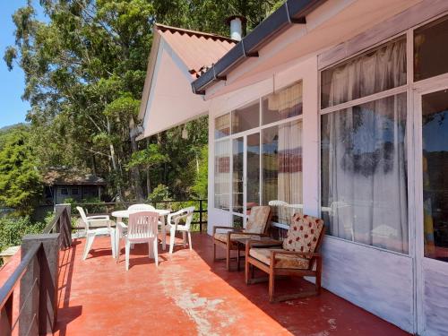 a porch of a house with chairs and a table at woods hut in Nuwara Eliya