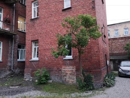 um edifício de tijolos vermelhos com uma árvore em frente em Sonata em Liepāja