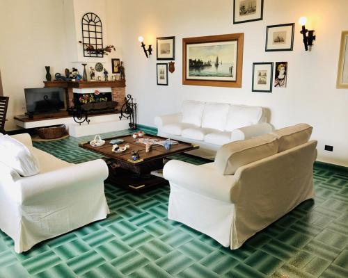 un soggiorno con divani bianchi e tavolino da caffè di Villa Luigina - seafront villa in Capo d'Orlando a Capo dʼOrlando