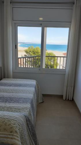 a bedroom with a large window with a view of the beach at Apartamentos Dins Mar Apto. 10 in Torredembarra