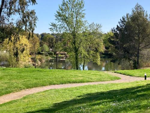 a path through a park with a pond and a bridge at Les Restanques vue mer Pressoir 3131 in Grimaud