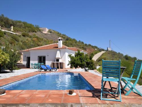 einen Pool mit zwei Stühlen und ein Haus in der Unterkunft Belvilla by OYO Villa Las Reinas in Arenas