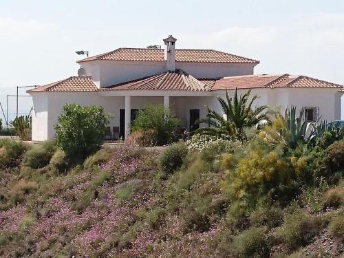 a house on the side of a hill with flowers at Belvilla by OYO Villa Bandoleros in Arenas