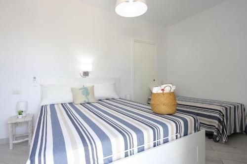 a white bedroom with a blue and white striped bed at Casa Manì in Anacapri
