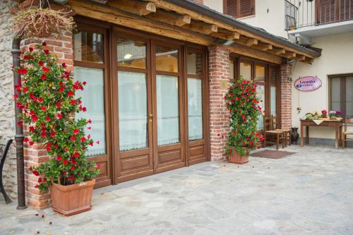 a brick building with a door and two plants with red flowers at Locanda Occitana Cà Bianca in Roccabruna