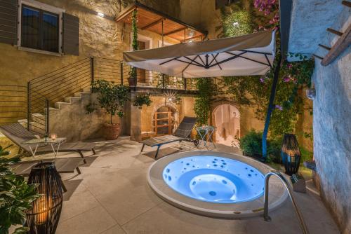 a hot tub in a courtyard with an umbrella at Corte Alma Spa and Luxury Home in Gargnano