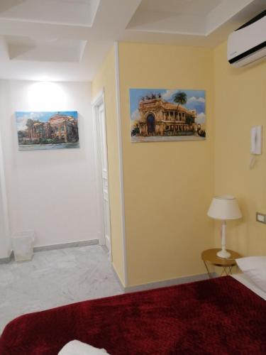 Zimmer mit 2 Gemälden an der Wand und einem Bett in der Unterkunft Federico 70 Giada Economy in Palermo
