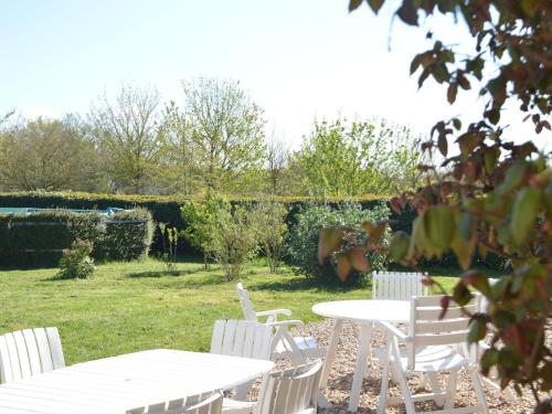 een groep witte tafels en stoelen in een tuin bij Snug Holiday Home in Chambourg Sur Indre with Pool in Chambourg-sur-Indre