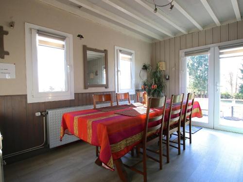 a dining room with a table and chairs and windows at Peaceful Chalet in Transinne with Patio in Libin