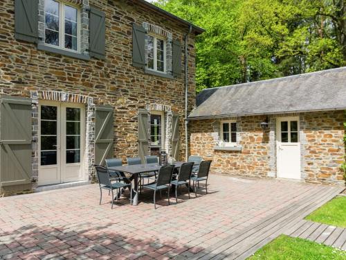 een patio met een tafel en stoelen voor een bakstenen gebouw bij Spacious Cottage with Private Garden in Ardennes in Frahan