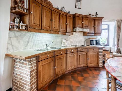 a kitchen with wooden cabinets and a brick floor at Stunning Holiday Home in Oombergen with Terrace and Garden in Zottegem