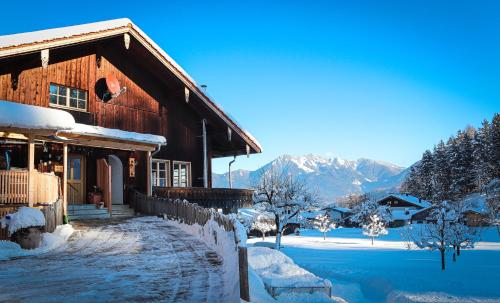 una cabaña de madera en la nieve con montañas en el fondo en Beim Mühltaler, en Schleching