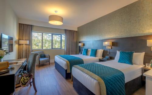 a hotel room with two beds and a desk at Glenroyal Hotel in Maynooth