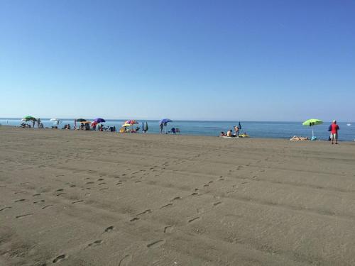 a group of people on a beach with umbrellas at Farmhouse near Montalto di Castro beaches in Montalto di Castro