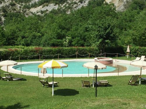 ein Pool mit Stühlen und Sonnenschirmen im Gras in der Unterkunft Belvilla by OYO Rosa Rossa in Apecchio