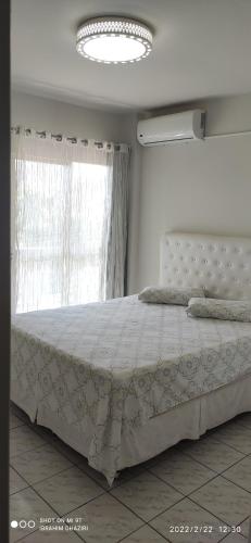 a bedroom with a bed with a white comforter and a window at Apartamento Foz Centro 01 in Foz do Iguaçu