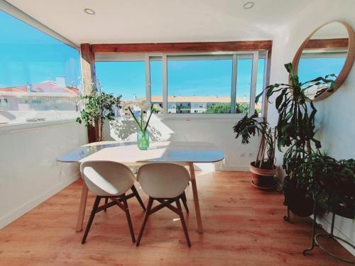 a table and two chairs in a room with windows at White House in Parede