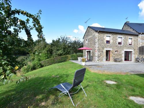 a chair sitting in the grass in front of a house at Cosy chalet with private garden in Normandy in Isigny-le-Buat