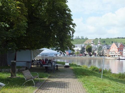 une passerelle à côté d'une rivière avec des personnes assises aux tables dans l'établissement Rezas Restaurant Gästehaus, à Oberbillig