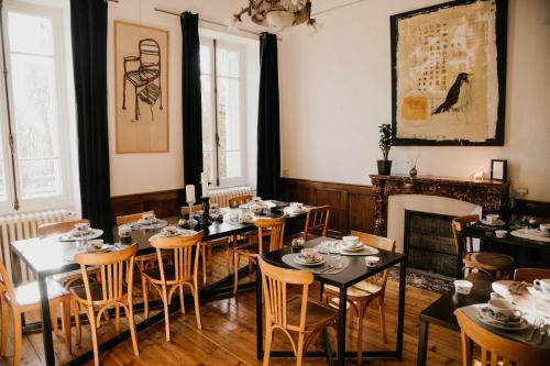 ein Esszimmer mit Tischen, Stühlen und einem Kamin in der Unterkunft Hotel Spa Azteca Barcelonnette in Barcelonnette