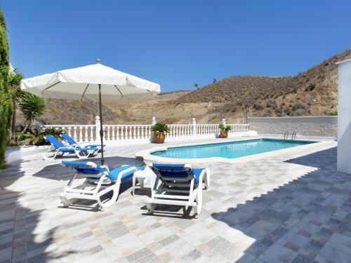 grupa krzeseł i parasol obok basenu w obiekcie Majestic Holiday Home in Mazarron with Private Pool w mieście Mazarrón