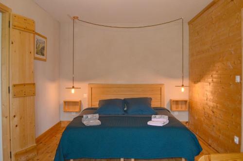 1 dormitorio con 1 cama azul y 2 toallas en Les ateliers du Cucheron, en Saint-Pierre-de-Chartreuse