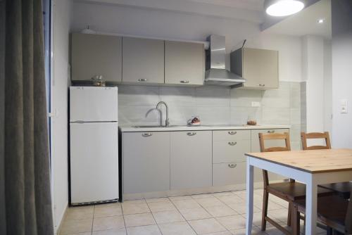 a kitchen with a white refrigerator and a table at Spyridoula Resort in Corfu in Gouvia