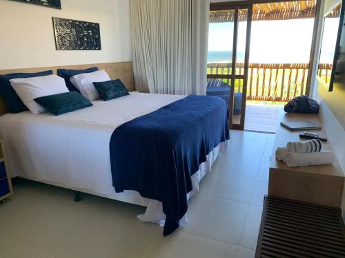a bedroom with a large bed with a view of the ocean at CASA Beira Mar Pé na Areia - Itacimirim Bahia in Camaçari