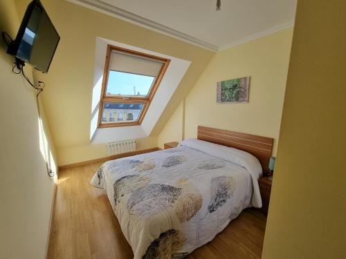 1 dormitorio con cama, ventana y TV en Dúplex en 1ª línea de playa, en Foz